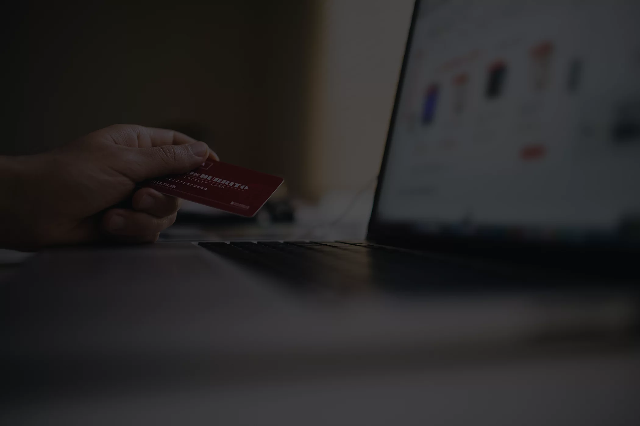 man holding credit card in front of computer